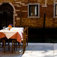 Venice-restaurant table set along the edge of a canal, landscape color photo