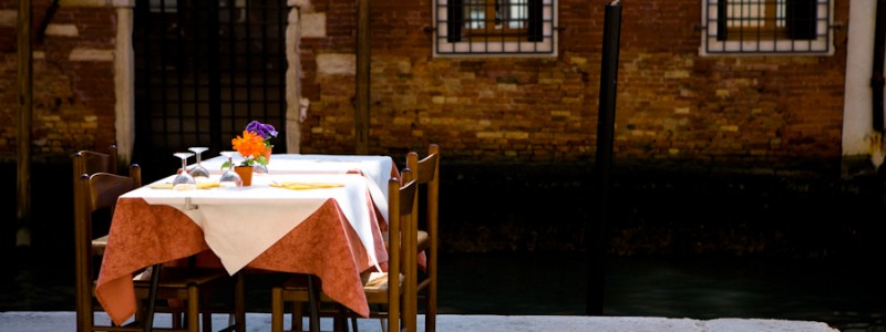 Venice-restaurant table set along the edge of a canal, landscape color photo