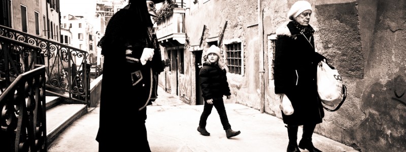 Venice - Little girl staring at man in carnival costume, black and white landscape photo